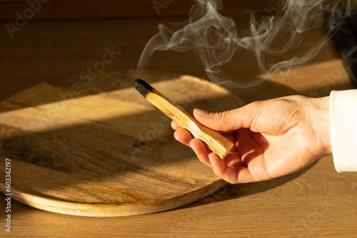 A woman's hand holds a smoking stick of the sacred palo santo tree. Ritual cleansing with sacred ibiocai, meditation, aromatherapy with incense photo