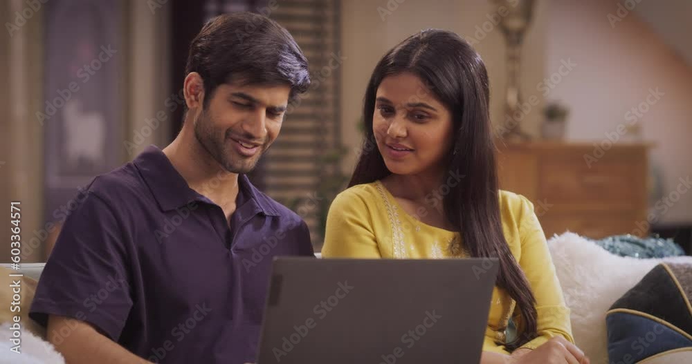 Smiling Indian Couple Using Laptop Computer at Home to do Online Shopping Together, Searching For Perfect Gifts, Seasonal Sales, And Exclusive Discounts. Gorgeous Girlfriend and Boyfriend Using e-shop Smiling Indian Couple Using Laptop Computer at Home to do Online Shopping Together, Searching For Perfect Gifts, Seasonal Sales, And Exclusive Discounts. Gorgeous Girlfriend and Boyfriend Using e-shop