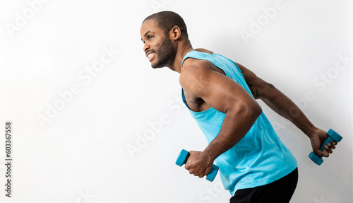 An African man is posing happily on a white background with a tank top and dumbbells. The adult works the triceps by lifting the dumbbell. Concept of weightlifting in handsome African Americans.