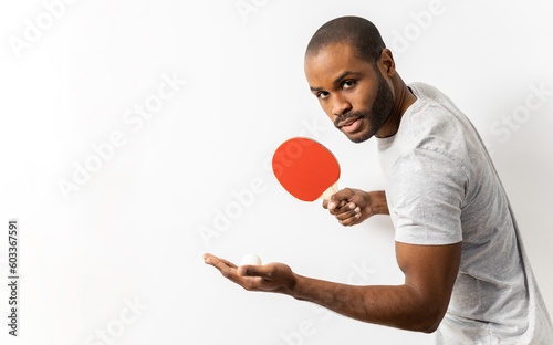 Fotografie An African man is posing in casual clothes with a ping-pong racket and a ball