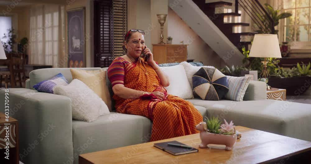 Elderly Indian Woman Using Smartphone at Home: Talking with Loved Ones, Relatives, Friends, Grandchildren. Beatiful Grandmother Sharing Heartwarming Moments. Medium Shot. Elderly Indian Woman Using Smartphone at Home: Talking with Loved Ones, Relatives, Friends, Grandchildren. Beatiful Grandmother Sharing Heartwarming Moments. Medium Shot.