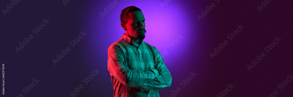 Portrait of man in checkered shirt posing with thoughtful, serious face against pink gradient studio background in neon light. Concept of human emotions, facial expression, lifestyle. Banner Portrait of man in checkered shirt posing with thoughtful, serious face against pink gradient studio background in neon light. Concept of human emotions, facial expression, lifestyle. Banner