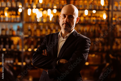 Portrait of a handsome mature gentleman in an evening restaurant. A man in a suit in an evening pub, restaurant, bar