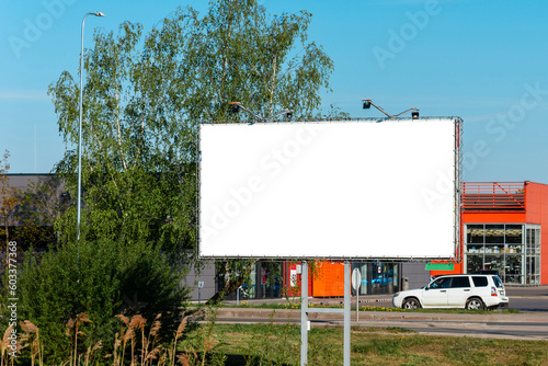 Advertising billboard mockup in the city on a sunny summer day.White Blank advertising billboard in the town.Near the shopping center, green trees turns green.