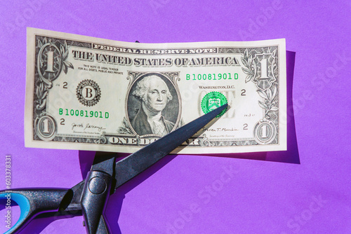 Financial concept.scissors cut money on purple background.Concept of spending money,scissors cut money of USA.