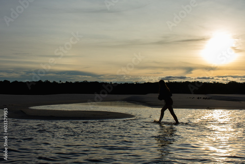 Jovem desfrutando da natureza na margem do rio ao anoitecer  photo