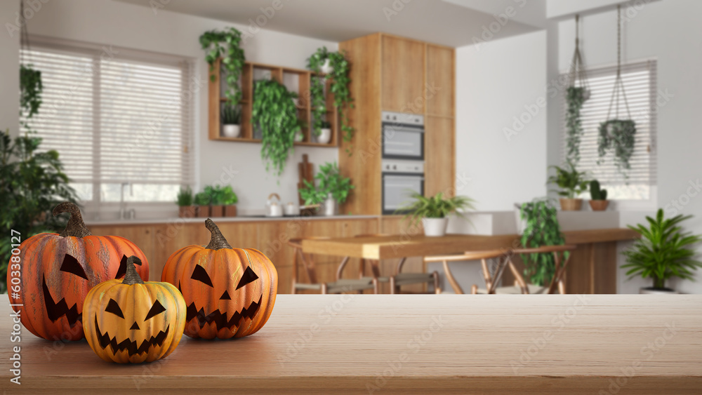 Obraz premium Halloween carved pumpkins on wooden table. Autumn decoration over interior design scene. Wooden modern kitchen with houseplants, urban jungle interior design concept