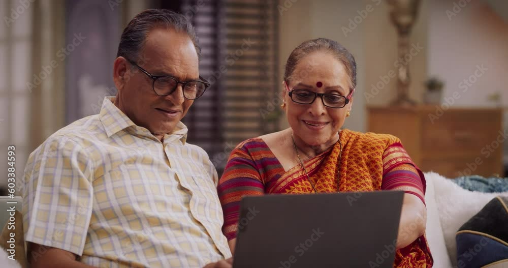 Beautiful Indian Eldrely Coupe Use Laptop at Home: Browsing Websites for Clothing, Products Sales, Choosing Best for Online Shopping.  Smiling Happy Grandma and Grandpa Enjoy Spending Time together