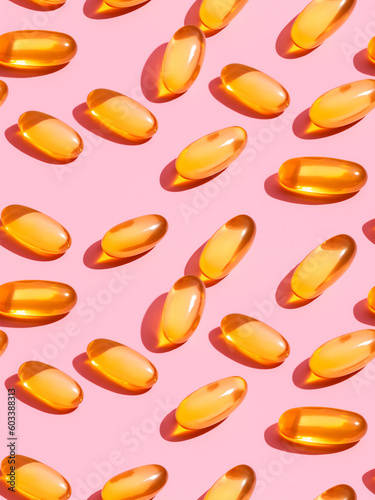 Orange pills scattered on pink surface photo