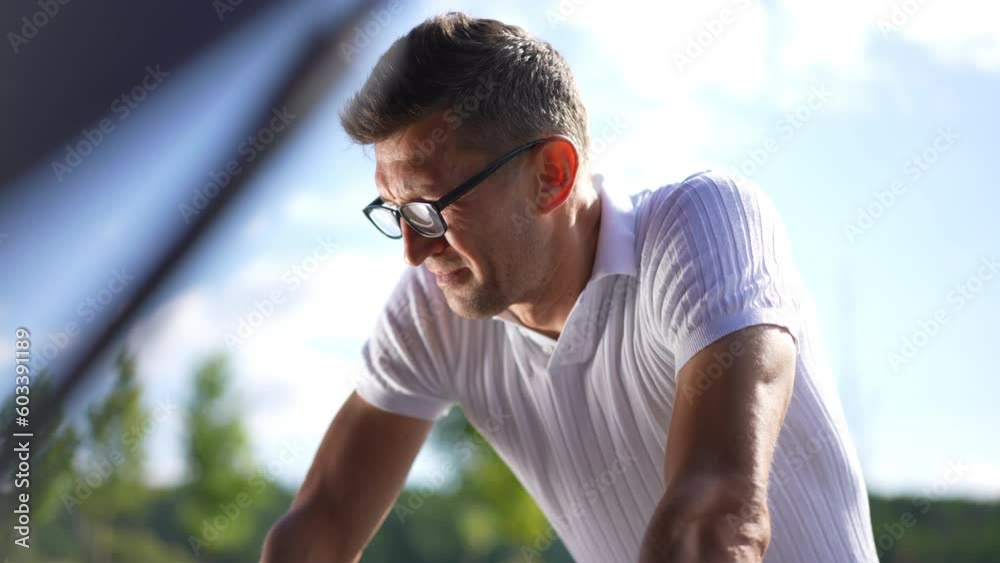 Troubled concentrated man leaning at car hood thinking examining engine. Portrait of thoughtful Caucasian adult driver in eyeglasses with broken automobile outdoors. Slow motion Troubled concentrated man leaning at car hood thinking examining engine. Portrait of thoughtful Caucasian adult driver in eyeglasses with broken automobile outdoors. Slow motion