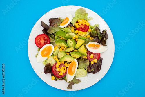 Delicious light vegetable salad made from tomatoes, canned corn, cucumber, lettuce, avocado and egg