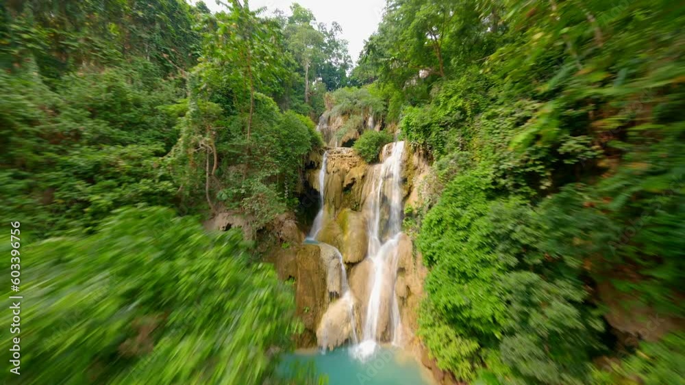 Dynamic FPV drone flight over stunning Kuang Si Waterfall near Luang Prabang in Laos, close to amazing water cascades and tropical trees.
