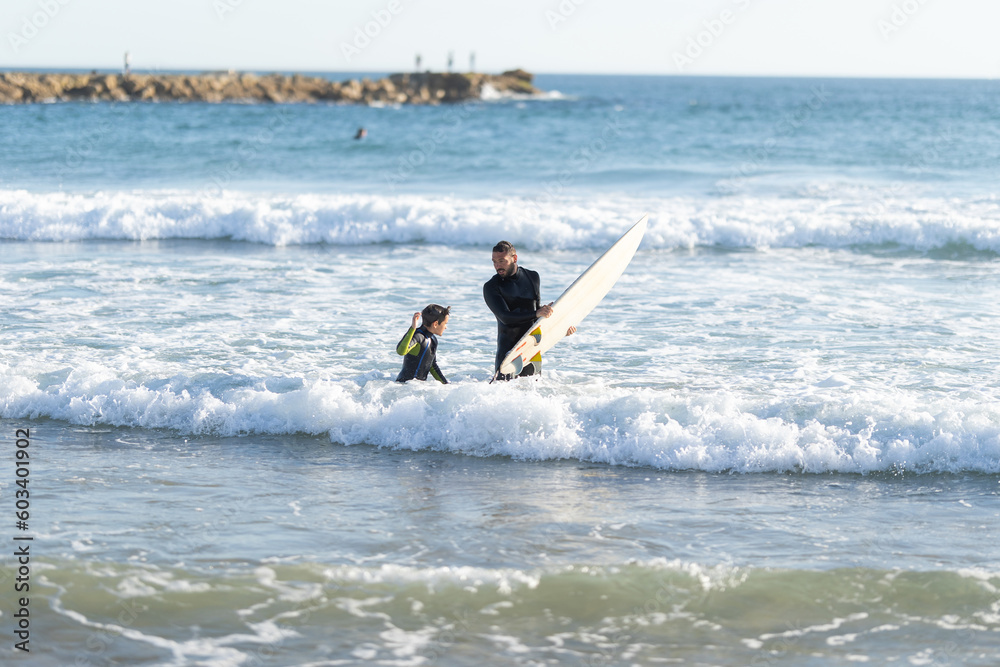 Father and son surfers in wetsuits in the sea Father and son surfers in wetsuits in the sea