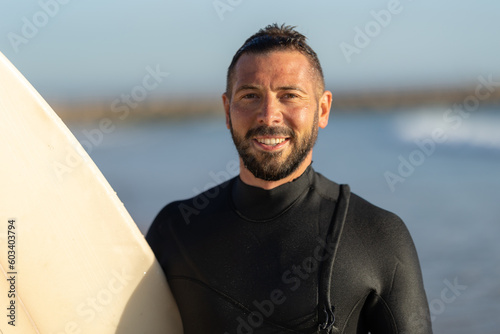 Smiling man surfer in a wetsuit