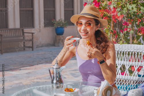 A girl in Dubai indulges in the simple pleasure of a cup of Arab coffee accompanied by the sweetness of fresh dates in a charming cafe photo