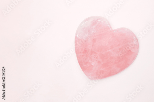 Isolated light rose quartz heart of stone. Pink gemstone heart