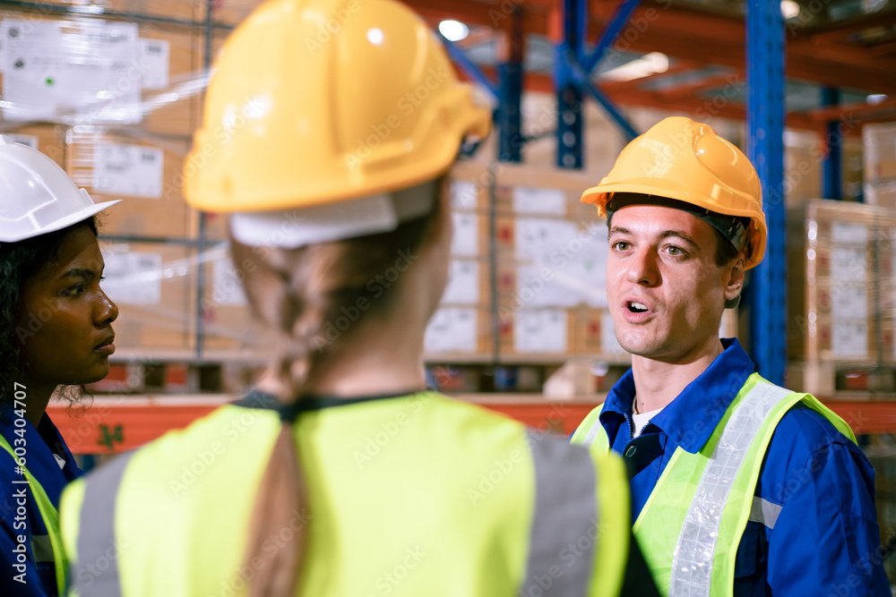 Male and Female workers wearing helmets in logistics distribution warehouse. Group of diversity warehouse worker meeting and checking list inventory in industry factory. Male and Female workers wearing helmets in logistics distribution warehouse. Group of diversity warehouse worker meeting and checking list inventory in industry factory.