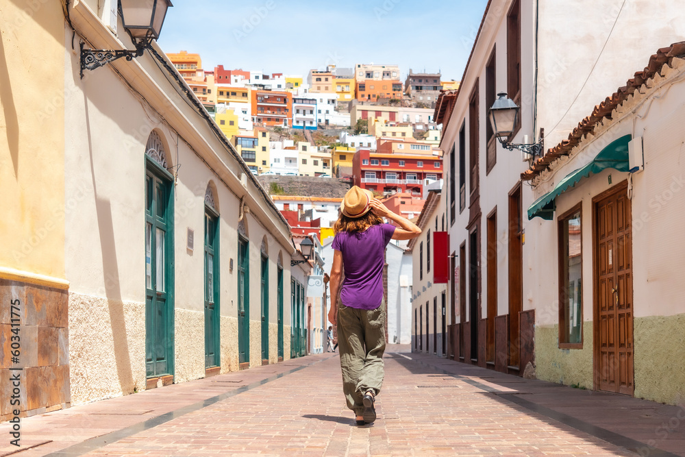 Fototapeta premium Woman on vacation walking through the city of San Sebastian de la Gomera next to the Iglesia De La Asuncion, Canary Islands
