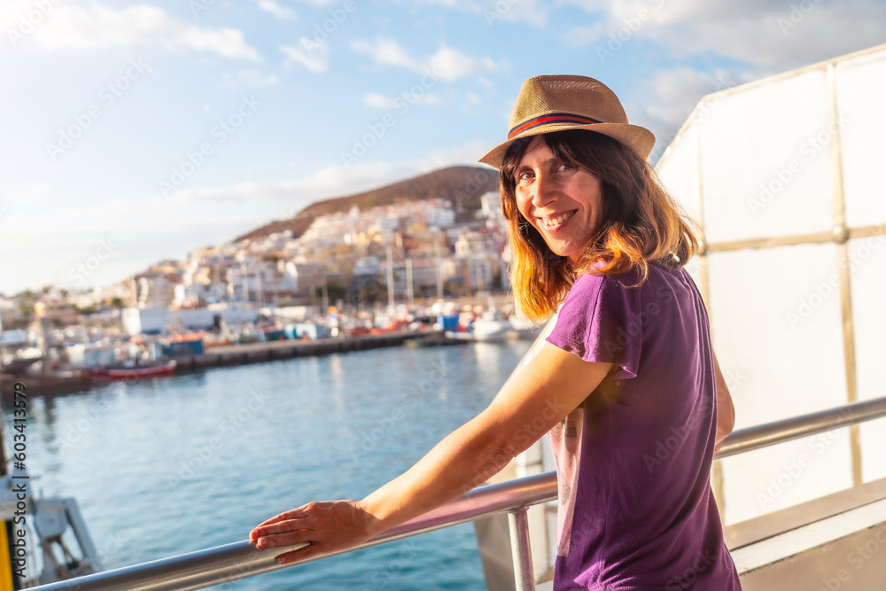 A female tourist from the Ferry and the city of Los Cristianos in the background on the island of Tenerife. Ferry coming from La Gomera, Canary Islands
