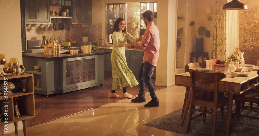 Young Couple Dancing and Having Fun in the Kitchen: Enjoying Each Other's Company and Playfully Moving to Music. With Joyful Laughter and Smiles, they Embrace the Music and Dance. Wide shot