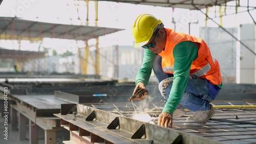 Workers at construction site weld metal structures of precast concrete slabs.