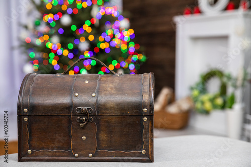 A brown old box in the foreground and a Christmas tree with Christmas lights in the background.