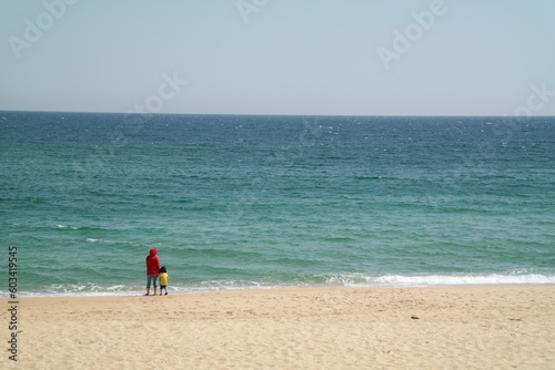 mother and son standing with their backs to the sea