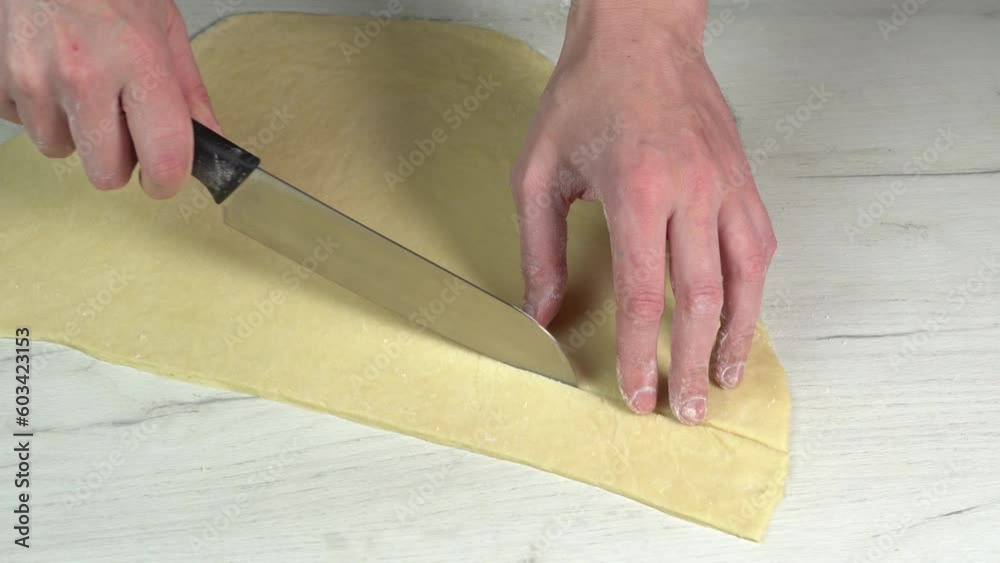 Cooking pasta at home. Chef cuts off a piece of rolled dough with a kitchen knife for baking. Cooking and dessert Cooking pasta at home. Chef cuts off a piece of rolled dough with a kitchen knife for baking. Cooking and dessert
