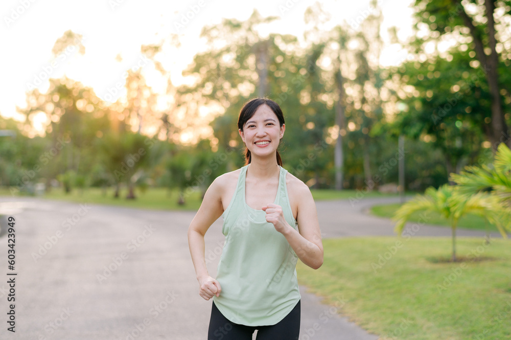 Fit Asian young woman jogging in park smiling happy running and enjoying a healthy outdoor lifestyle. Female jogger. Fitness runner girl in public park. healthy lifestyle and wellness being concept Fit Asian young woman jogging in park smiling happy running and enjoying a healthy outdoor lifestyle. Female jogger. Fitness runner girl in public park. healthy lifestyle and wellness being concept