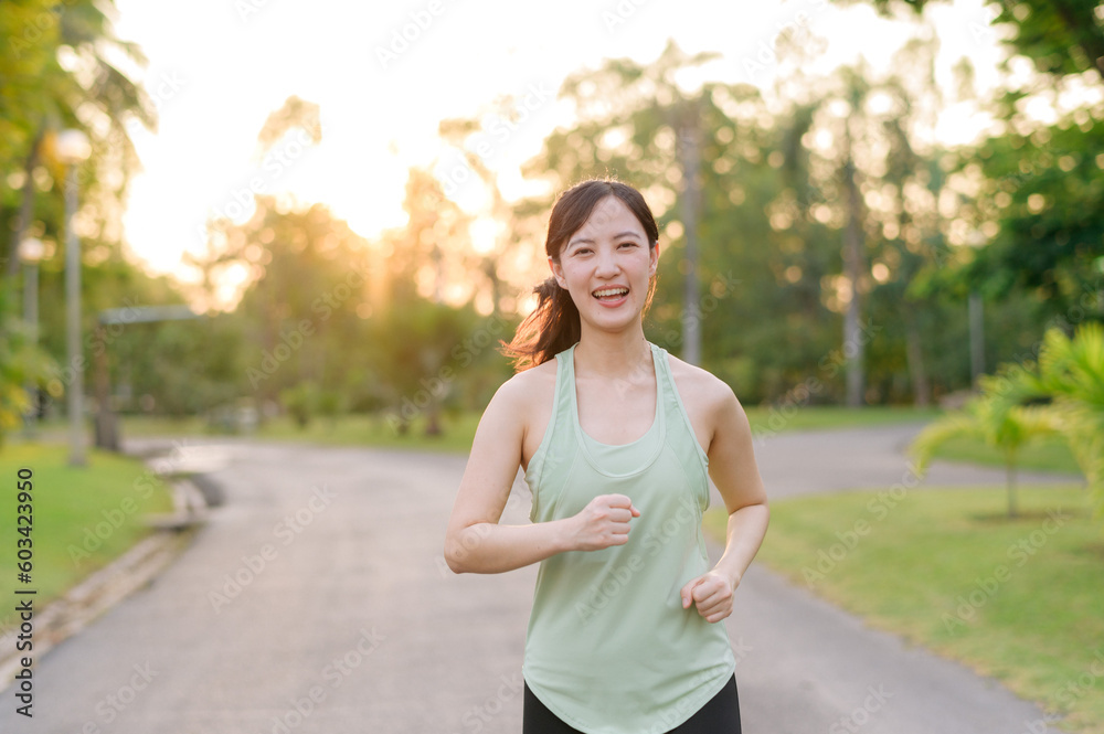 Fit Asian young woman jogging in park smiling happy running and enjoying a healthy outdoor lifestyle. Female jogger. Fitness runner girl in public park. healthy lifestyle and wellness being concept Fit Asian young woman jogging in park smiling happy running and enjoying a healthy outdoor lifestyle. Female jogger. Fitness runner girl in public park. healthy lifestyle and wellness being concept