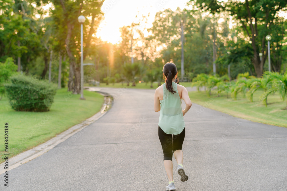 Fit Asian young woman jogging in park smiling happy running and enjoying a healthy outdoor lifestyle. Female jogger. Fitness runner girl in public park. healthy lifestyle and wellness being concept Fit Asian young woman jogging in park smiling happy running and enjoying a healthy outdoor lifestyle. Female jogger. Fitness runner girl in public park. healthy lifestyle and wellness being concept