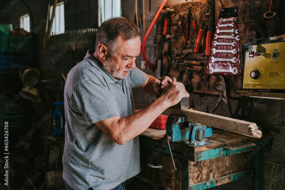 Aged carpenter using plane and working in garage Aged carpenter using plane and working in garage