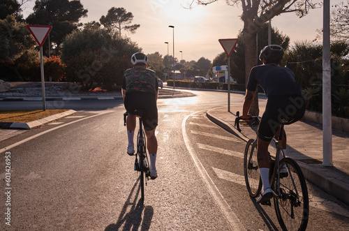 Close up back view of cycling group training on a road bicycles at sunset in the mountains.Training for competition.Practicing cycling on open country road.Spain © Ketrin