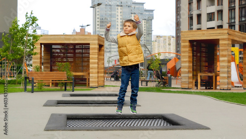 Slow motion of little boy jumping and having fun on trampoline in new park at city block. Active child, sports and development, kids playing outdoors © Кирилл Рыжов