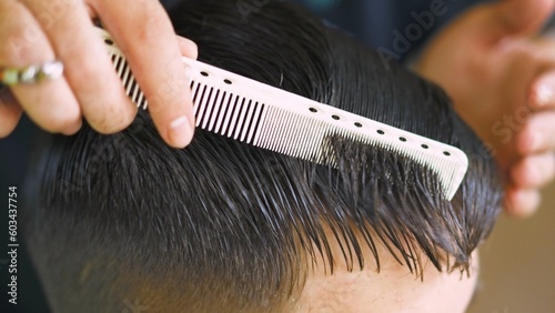hairstylist combing the fringe of a young man with a white comb