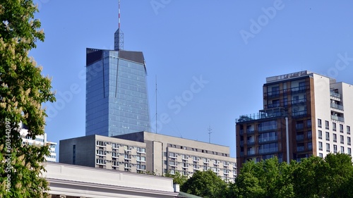 Inspiring view of the modern city. The wall of the buildings of glass and metal against trees. Corporate buildings and ecological, view of modern building with blue sky and green trees