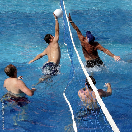 4 men playing water polo in a swimming pool photo