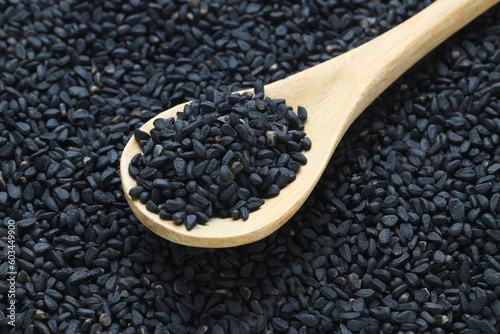 Black cumin seeds and essential oil with bowl and wooden shovel or spoon. Nigella Sativa in glass bottle. Organic herbal medicine for many diseases