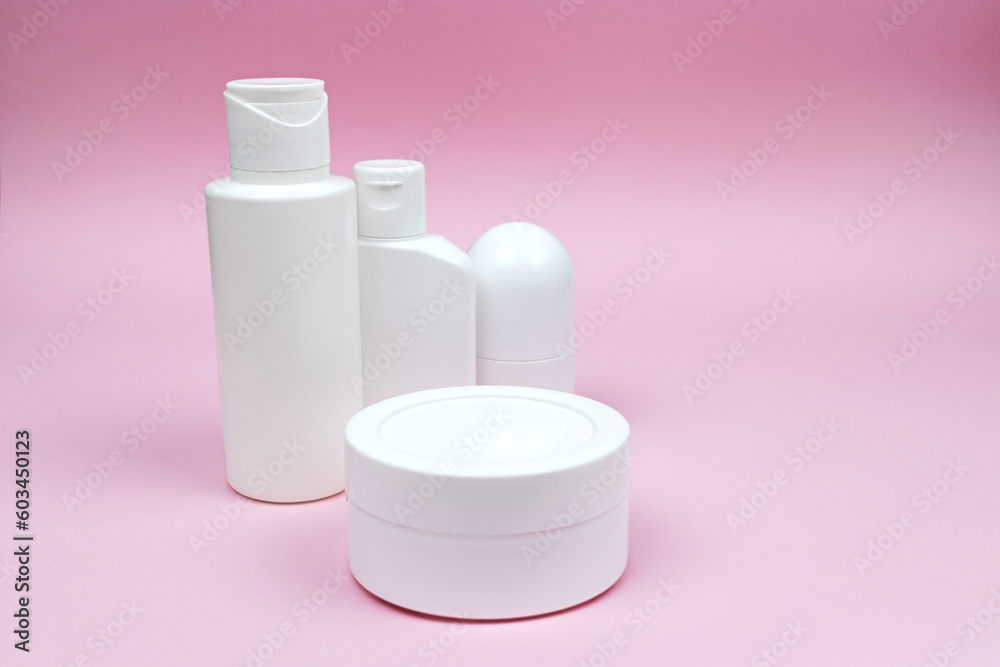 Set of white plastic cosmetic bottles, jar, and deodorant mock-up on the pink background. Skincare and body care concept, cosmetics, beauty industry. Set of white plastic cosmetic bottles, jar, and deodorant mock-up on the pink background. Skincare and body care concept, cosmetics, beauty industry.