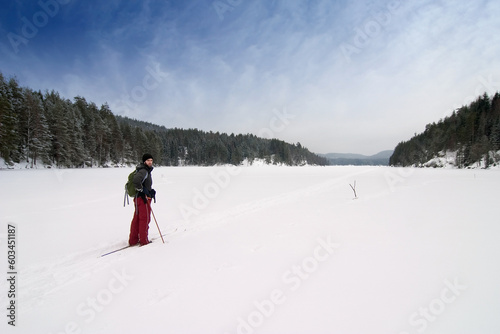 A cross country skiier out on a refreshing trip over a frozen lake.