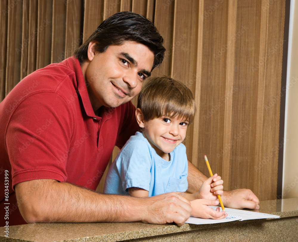 Hispanic father and son smiling at viewer with homework. Hispanic father and son smiling at viewer with homework.