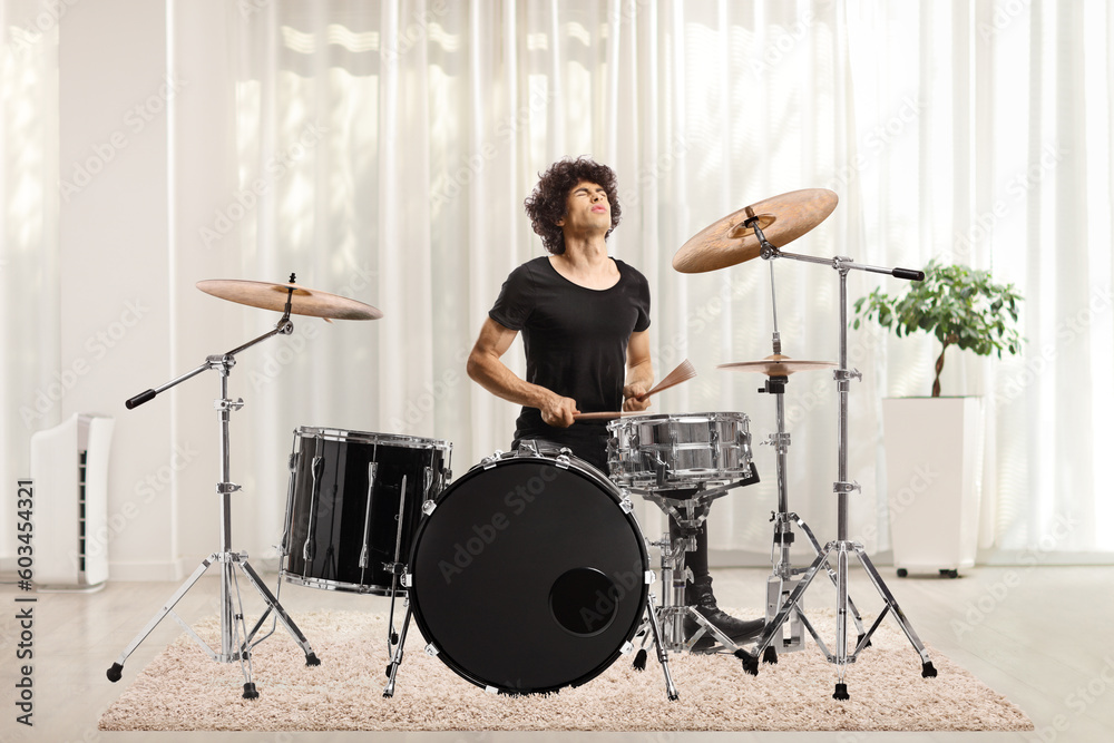 Fototapeta premium Young female playing drums in a room