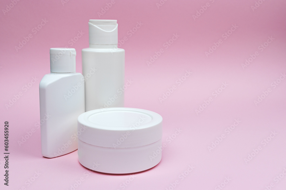 Set of white plastic cosmetic bottles and jar mock-up on the pink background. Skincare and body care concept, cosmetics, beauty industry. Set of white plastic cosmetic bottles and jar mock-up on the pink background. Skincare and body care concept, cosmetics, beauty industry.