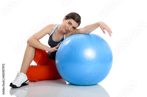 Beautiful young woman relaxinx with a core ball isolated on white