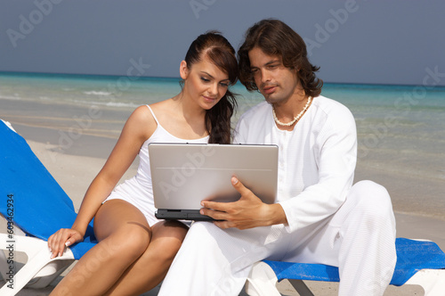 Romantic young couple working on laptop computer at the beach © Designpics