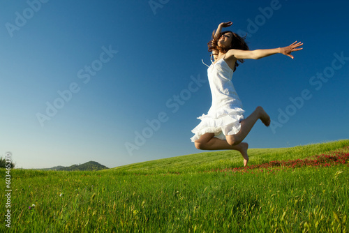 Beautiful young woman jumping on the field