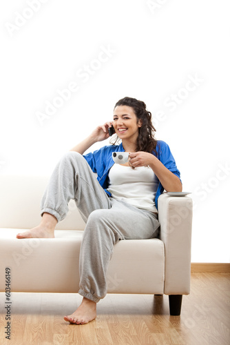 Portrait of a girl seated on the couch and making a phone call