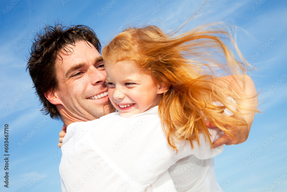 father and daughter having fun outdoors, dressed in white and with blue sky in background father and daughter having fun outdoors, dressed in white and with blue sky in background
