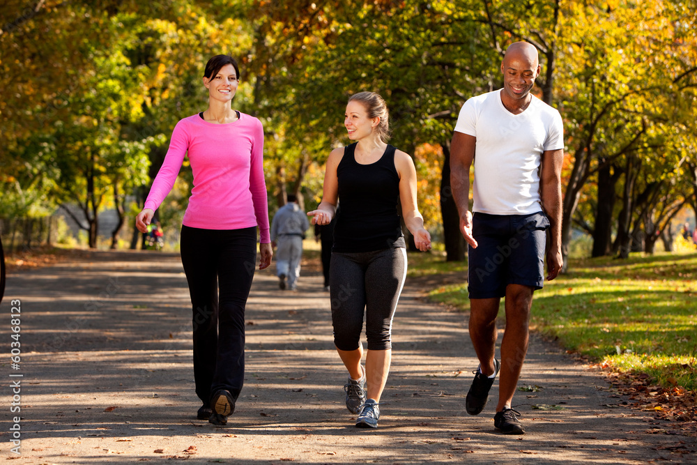 Three people walking in a park, getting some exercise Three people walking in a park, getting some exercise