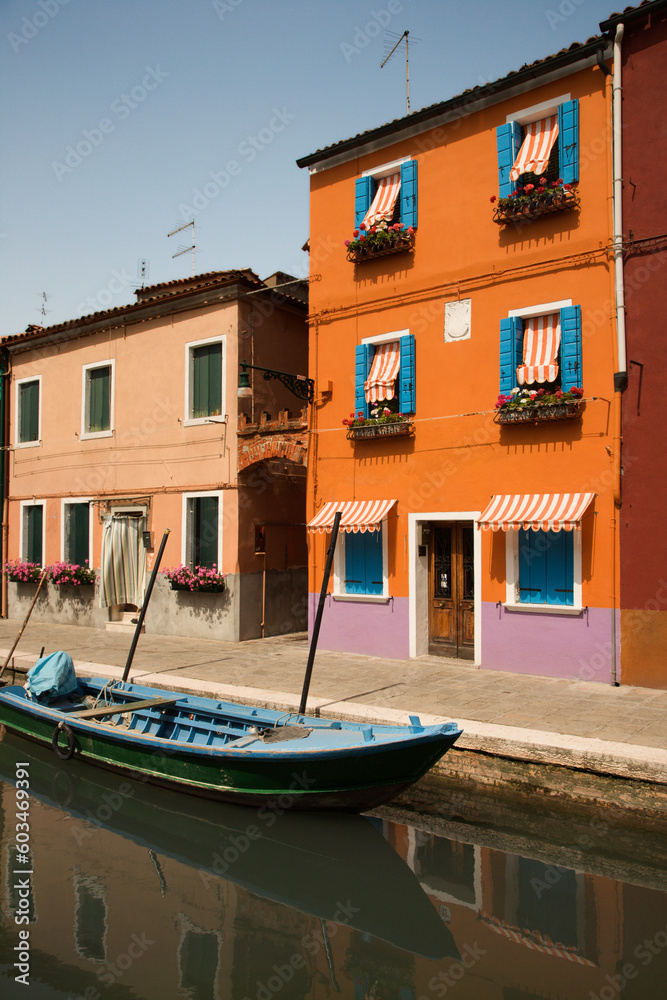 Buildings and boat on a canal in Venice, Italy, under blue sky. Vertical shot.